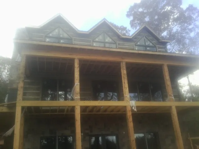 Dormers and porch framing on a large log home under construction — Roof Coating work by our crew in Levittown