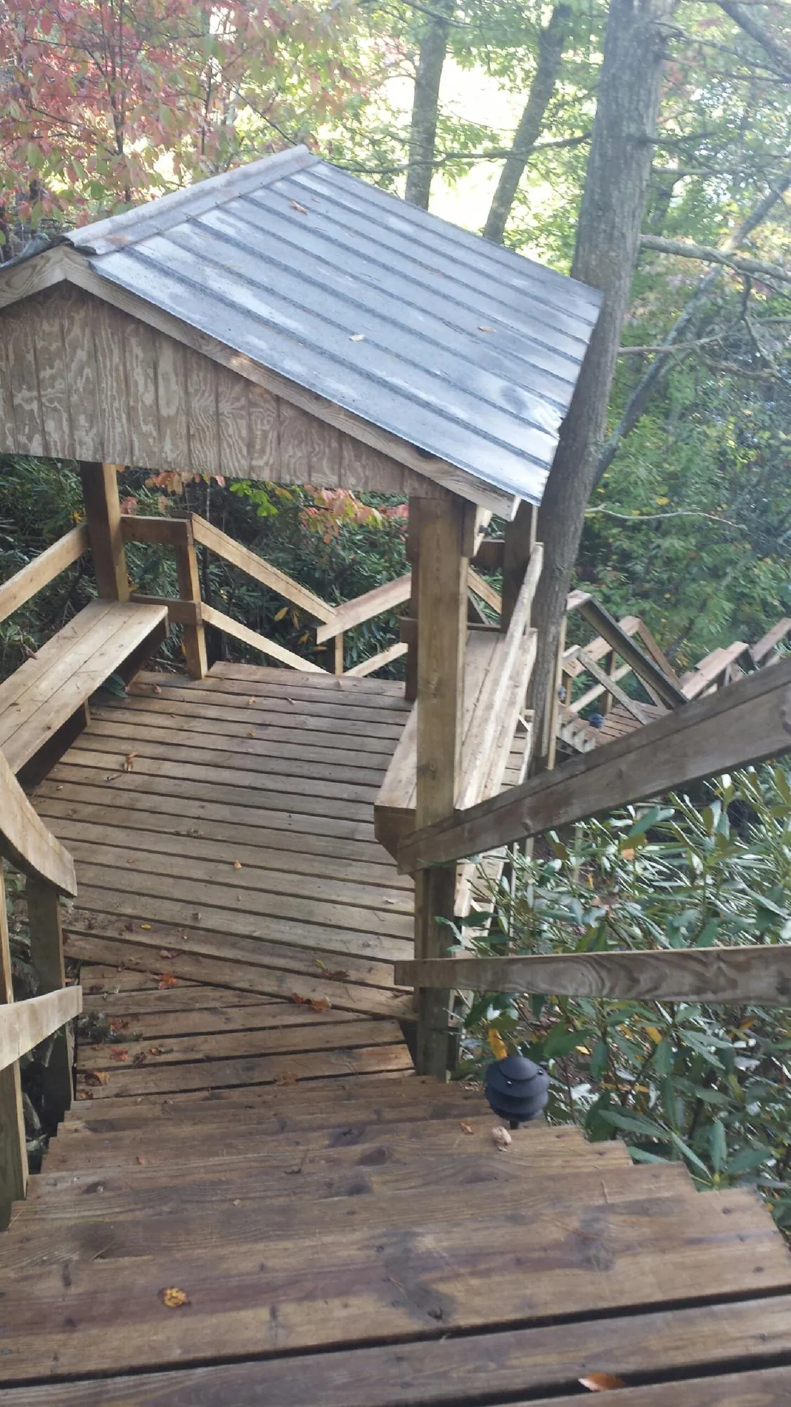 Metal roofed shelter over wooden steps on a wooded walkway — Skylight Repair & Installation work by our crew in Levittown